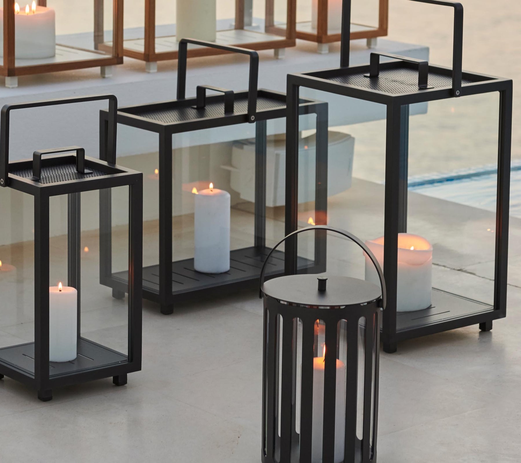 Faroles decorativos en varios tamaños con velas en su interior, creando una atmósfera acogedora.