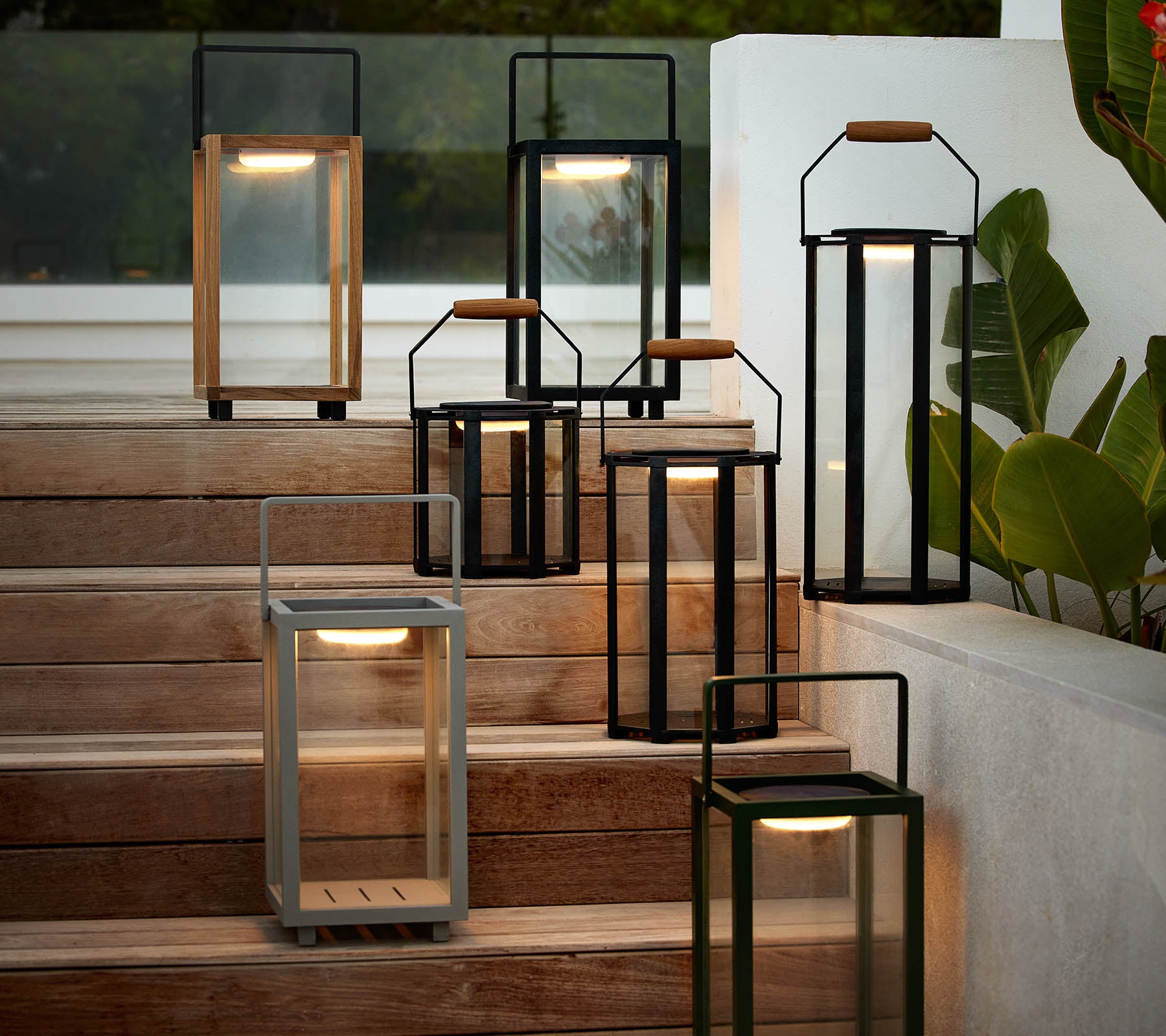 Una colección de faroles modernos en varios estilos y colores dispuestos en una escalera, destacando su diseño elegante y su cálida iluminación.