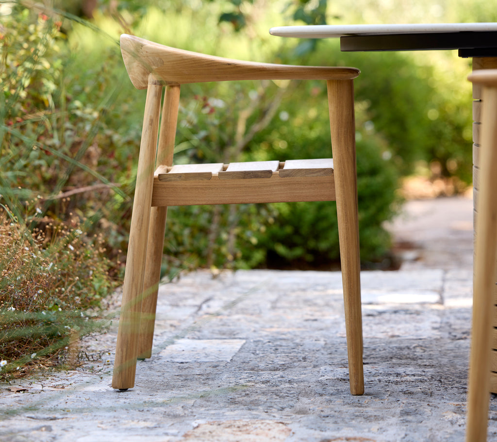 Silla de madera moderna al lado de una mesa negra en un entorno al aire libre.