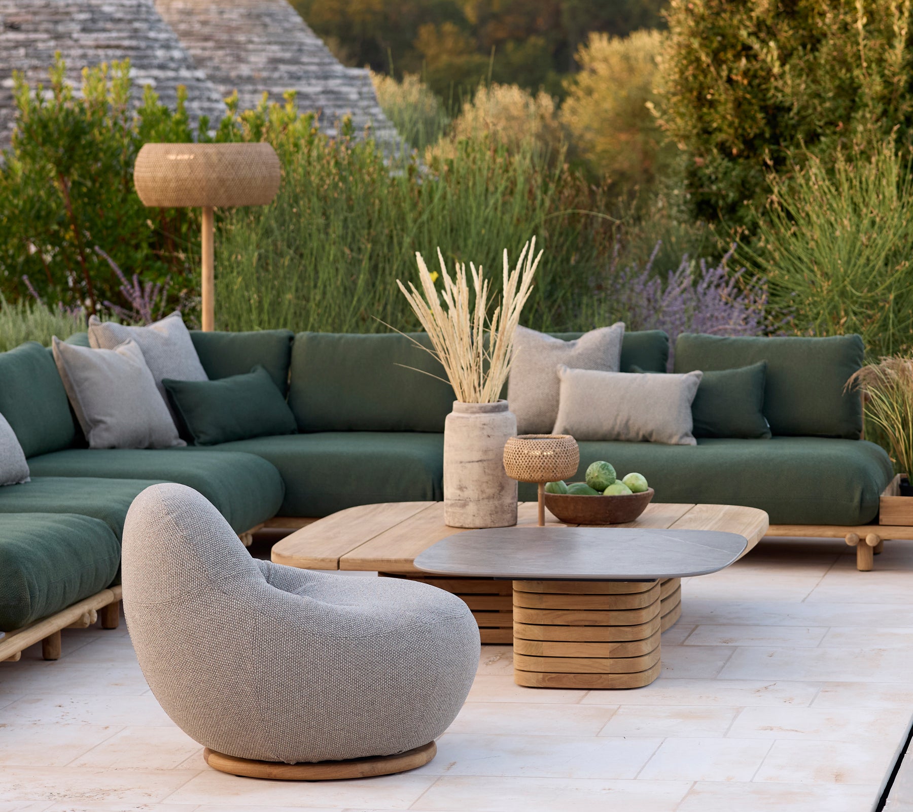 Área de salón moderna con un sofá verde, una silla gris y una mesa de café redonda.