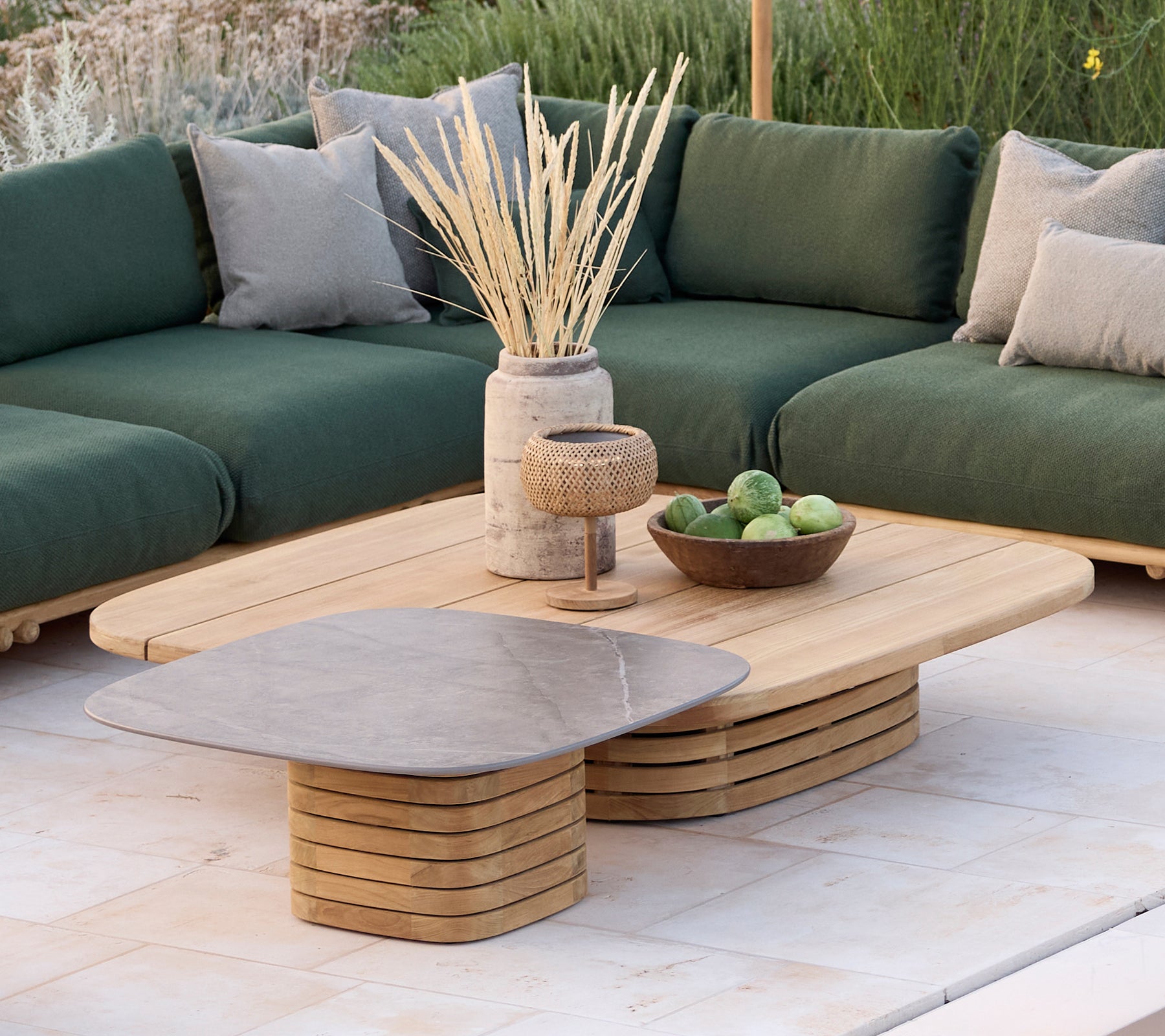 Área de salón moderna con un sofá verde con cojines, una mesa de café de madera y artículos decorativos.