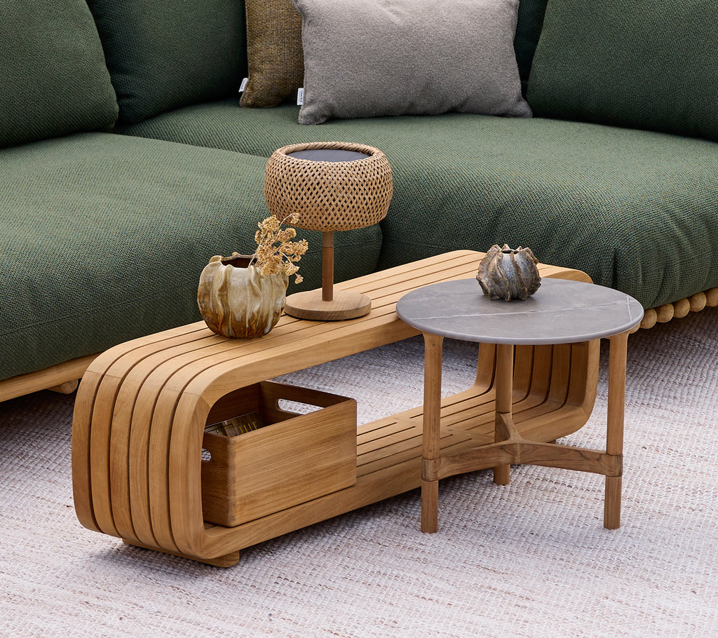 Mesa de café de madera moderna con una mesa auxiliar gris, lámpara y jarrón decorativo en un ambiente de salón.