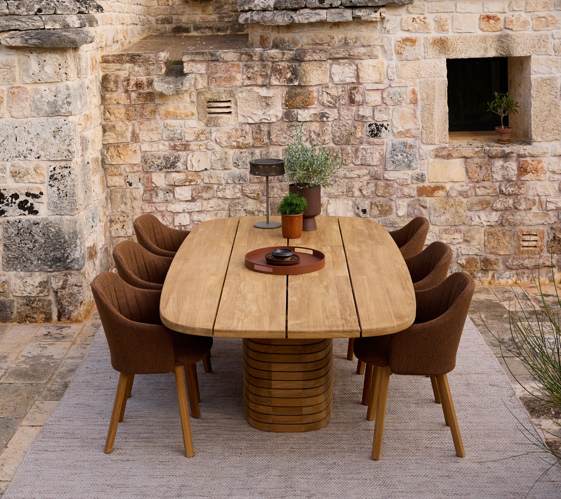 Mesa de comedor de madera moderna rodeada de sillas marrones en un entorno rústico.