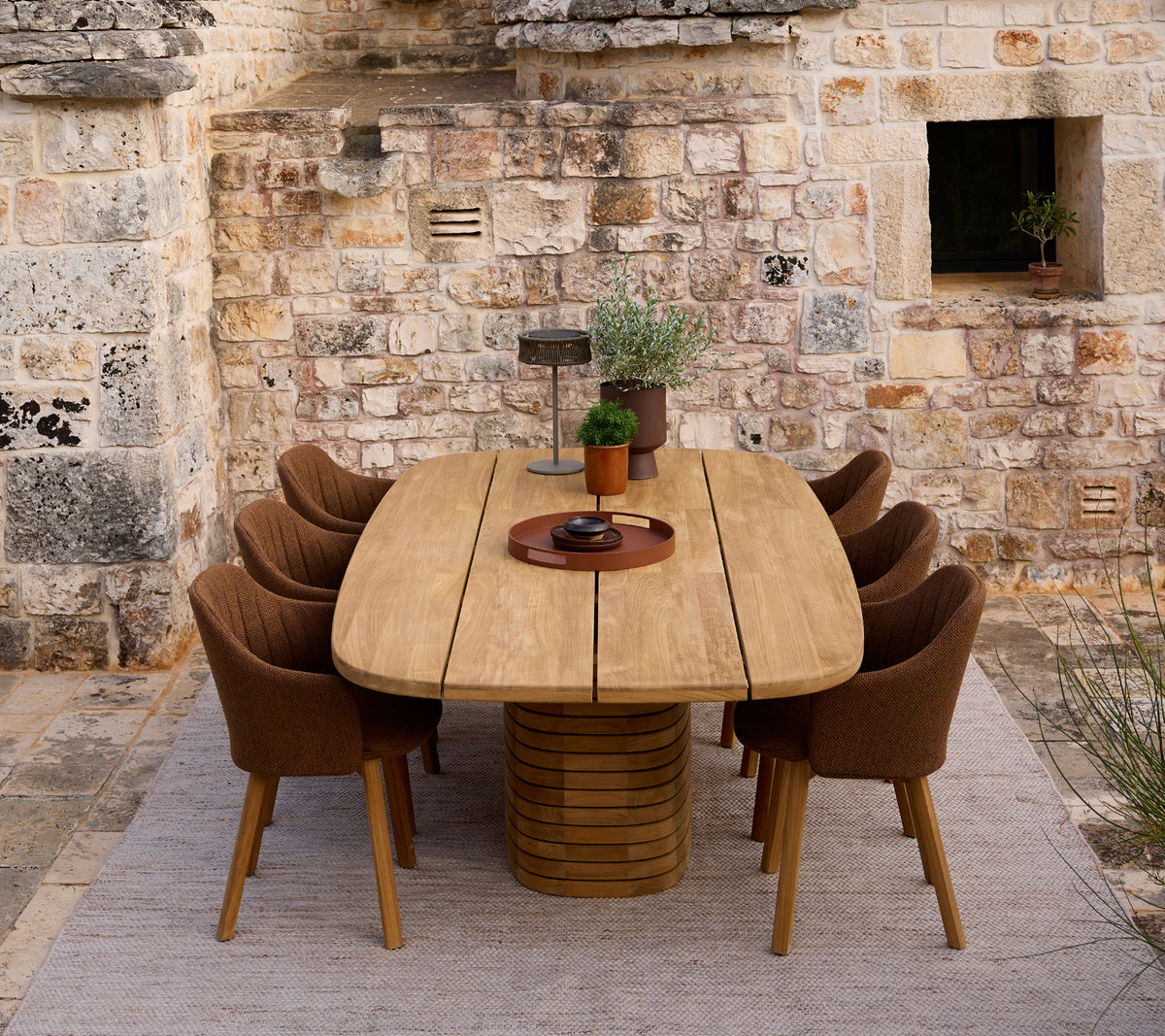 Mesa de comedor de madera moderna rodeada de sillas marrones en un entorno rústico.