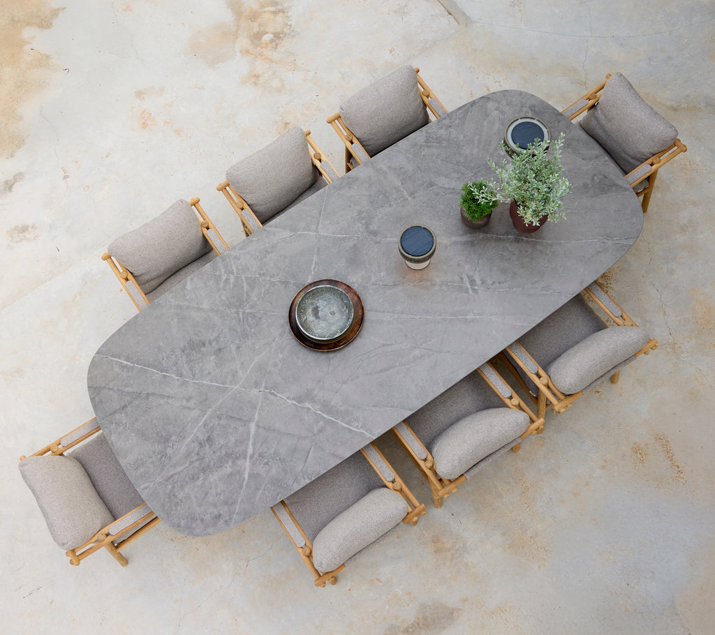 Configuración moderna de comedor con una mesa gris, cojines beige y sillas de madera.
