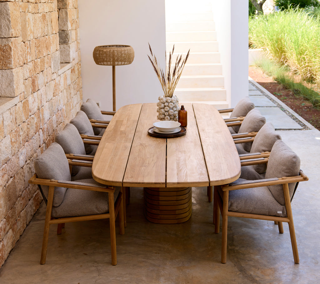 Configuración moderna de comedor con mesa de madera, cojines grises y sillas de madera.