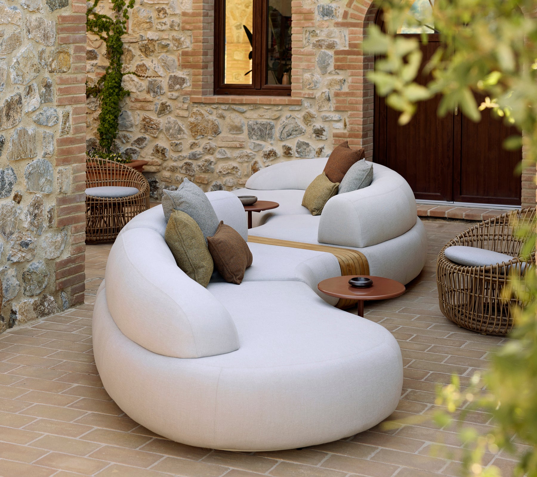 Lounge suave con una silla redonda Nest y una mesa de café Glaze, complementada con cojines decorativos en un ambiente tranquilo.
