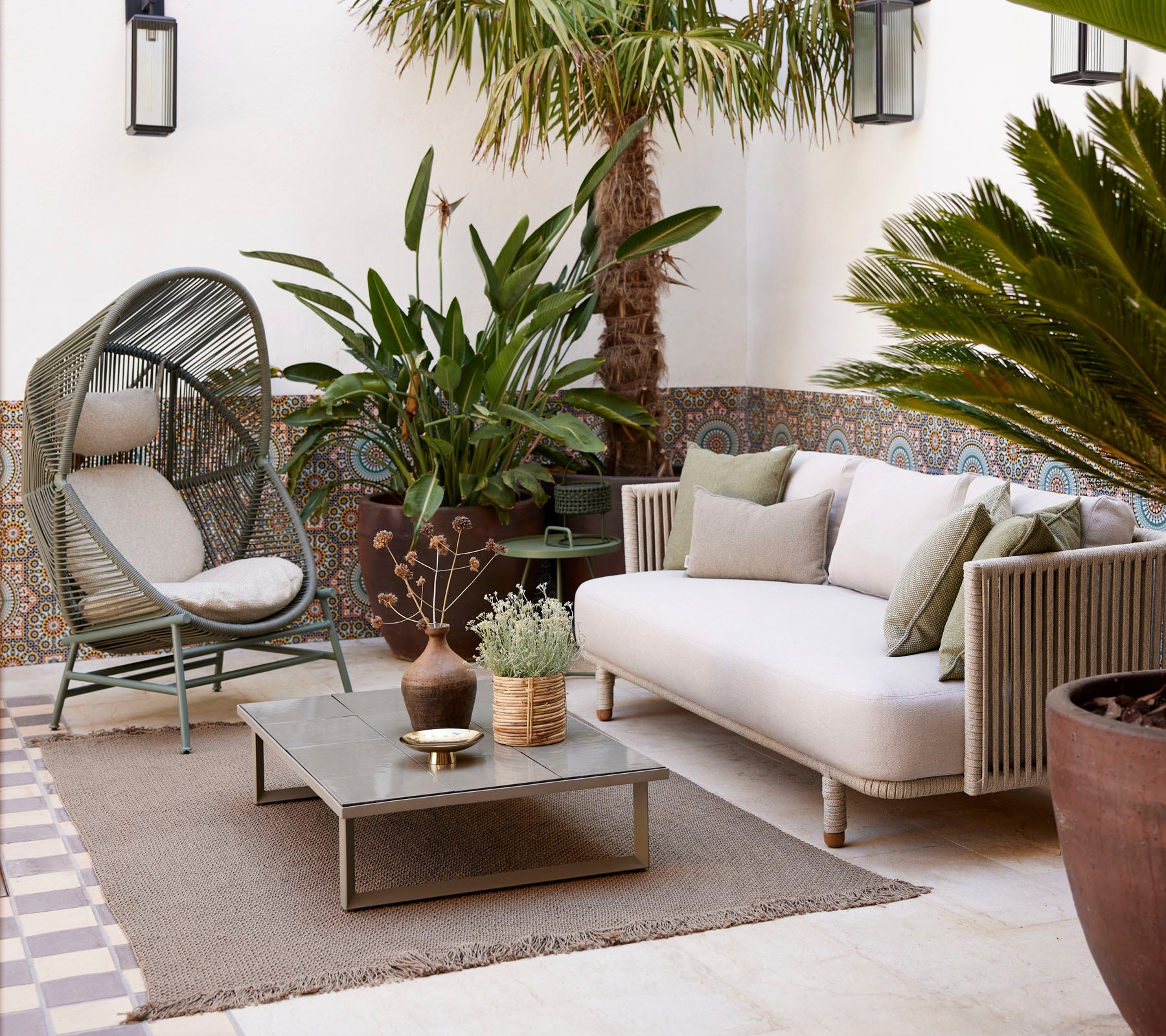 Área de estar acogedora con plantas, alfombras texturizadas y una mesa de café moderna, que ofrece una atmósfera serena y acogedora.