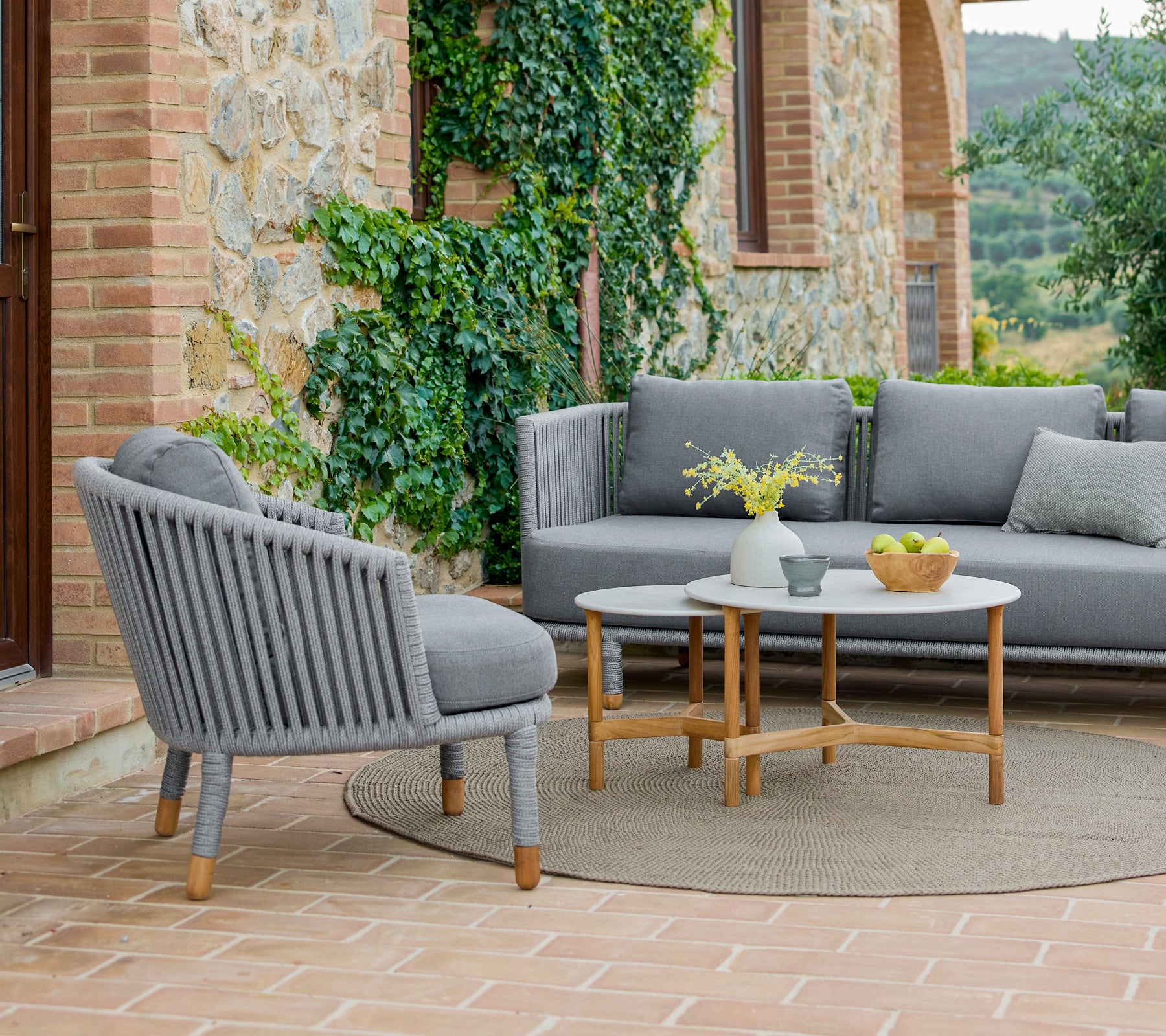 Un conjunto de sillón y mesa de café con un diseño moderno, rodeado de vegetación y una atmósfera cálida y acogedora.