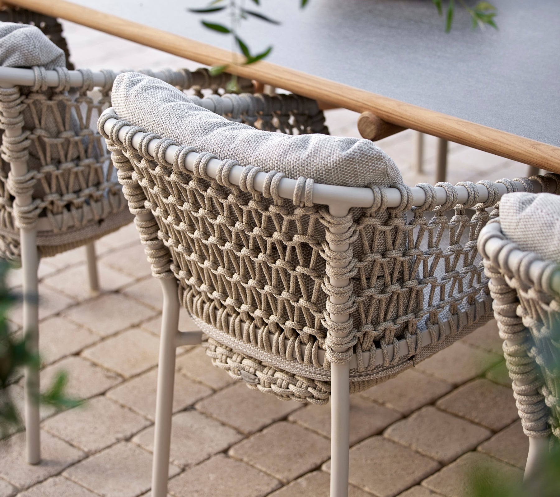 Sillas de comedor acogedoras con un diseño tejido y suaves cojines, perfectas para cenar al aire libre con estilo.