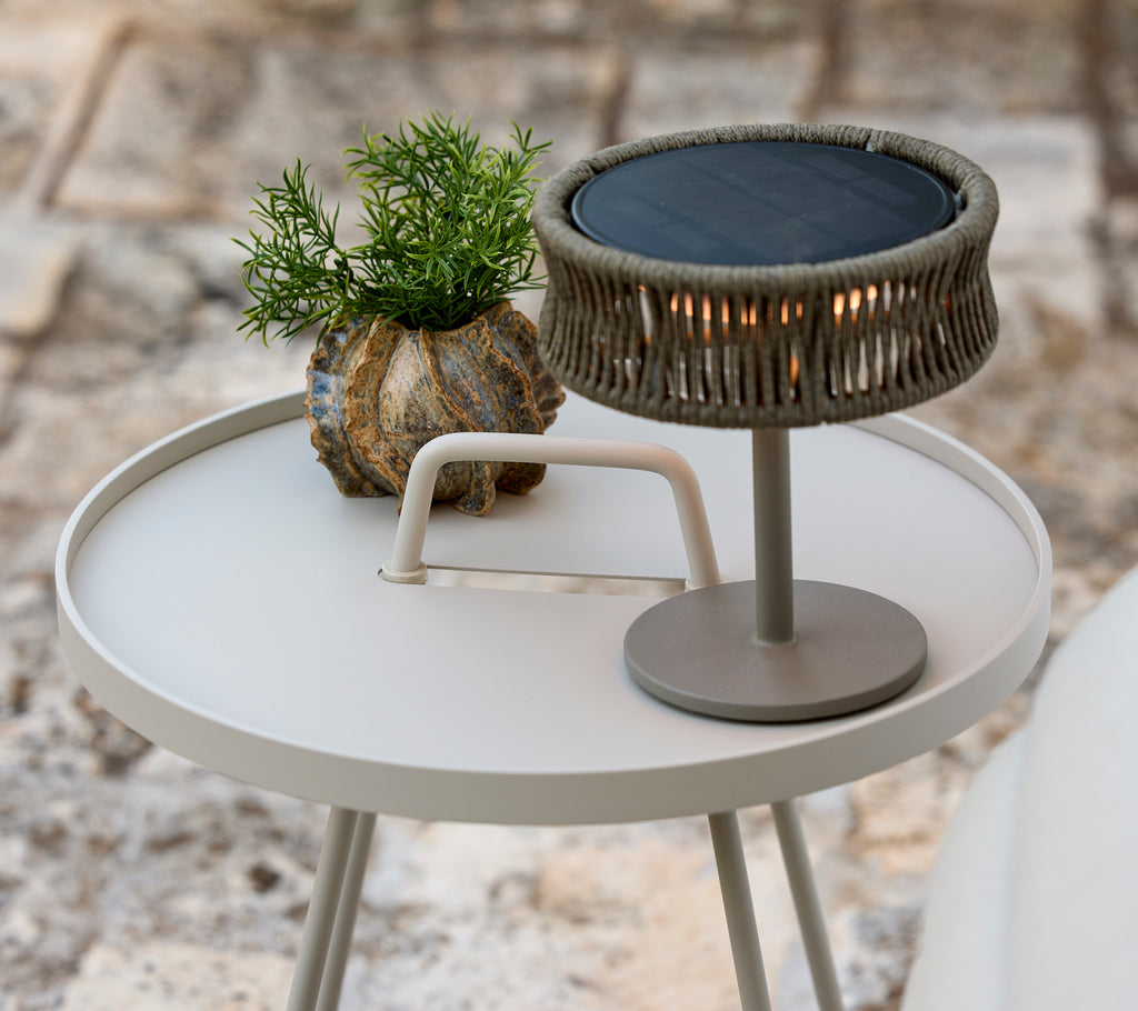 Mesa auxiliar moderna gris con una planta verde y una lámpara de mesa elegante.