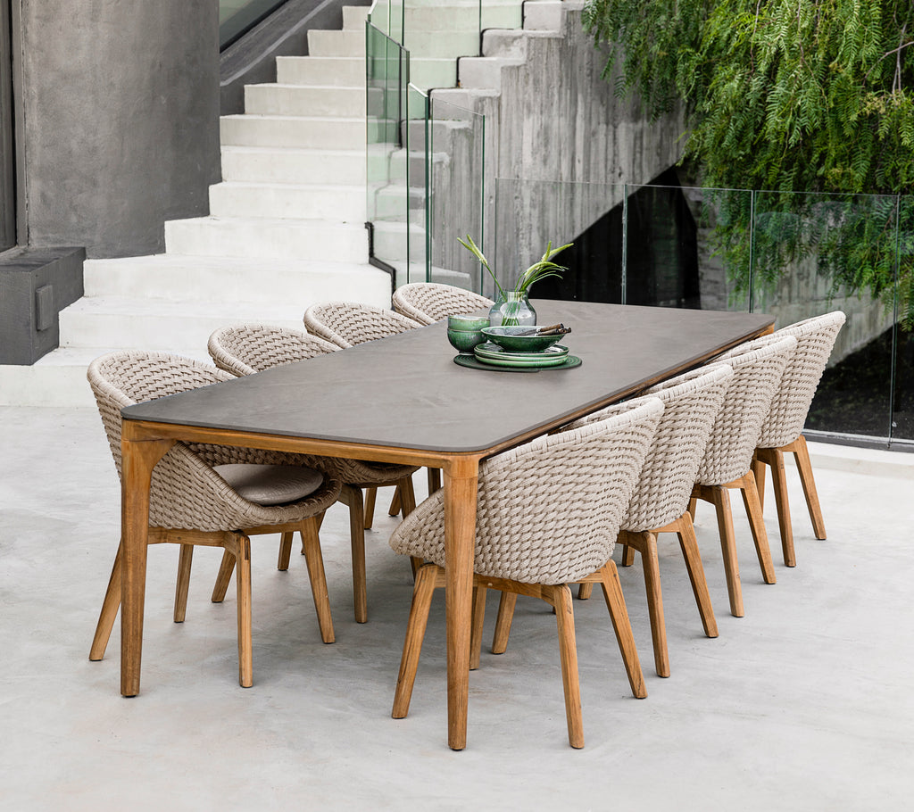 Mesa de comedor marrón moderna con sillas trenzadas en un entorno contemporáneo.