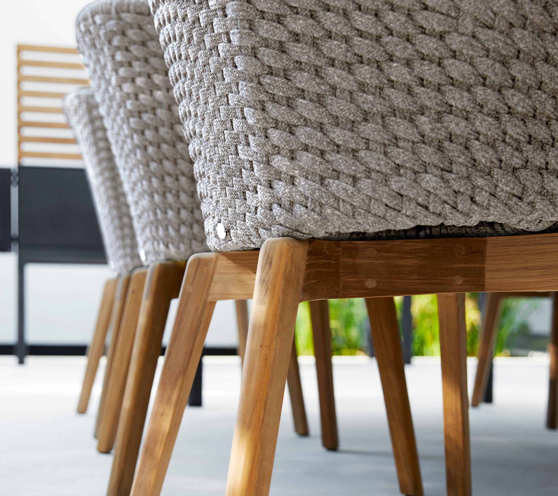 Silla moderna gris con un diseño tejido y patas de madera.