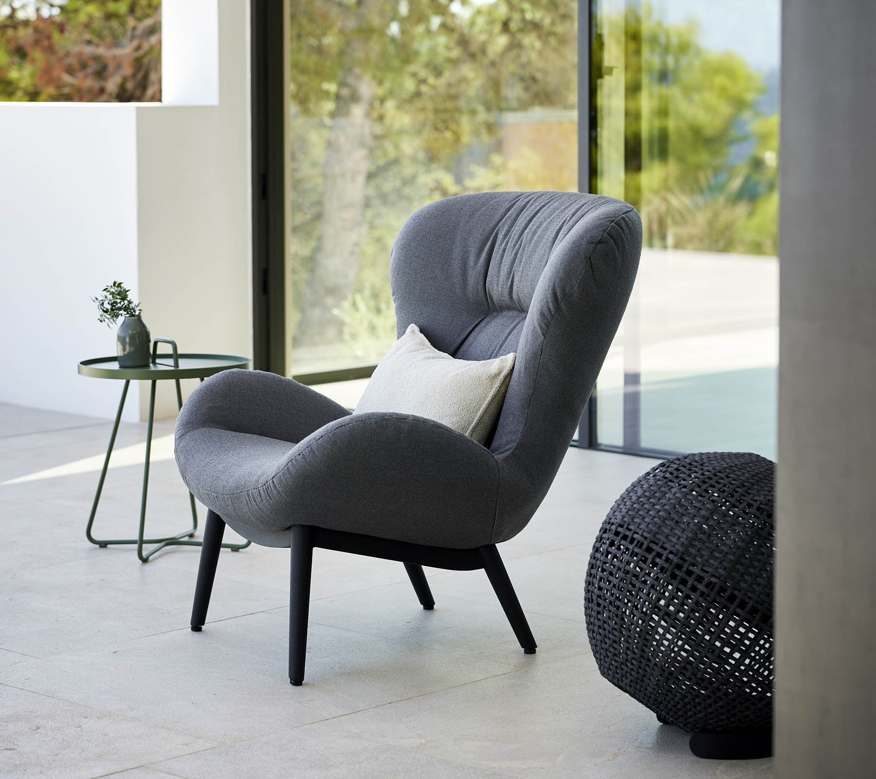 una silla de lounge serena con un diseño moderno, que cuenta con tapicería suave y patas elegantes, acompañada de una pequeña mesa lateral y acentos decorativos.