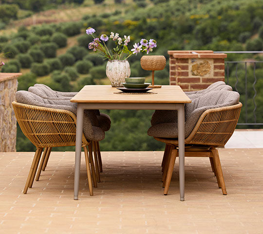 Configuración de comedor elegante con una mesa de comedor Core y sillas Stay, adornada con un jarrón de flores, creando un ambiente acogedor.