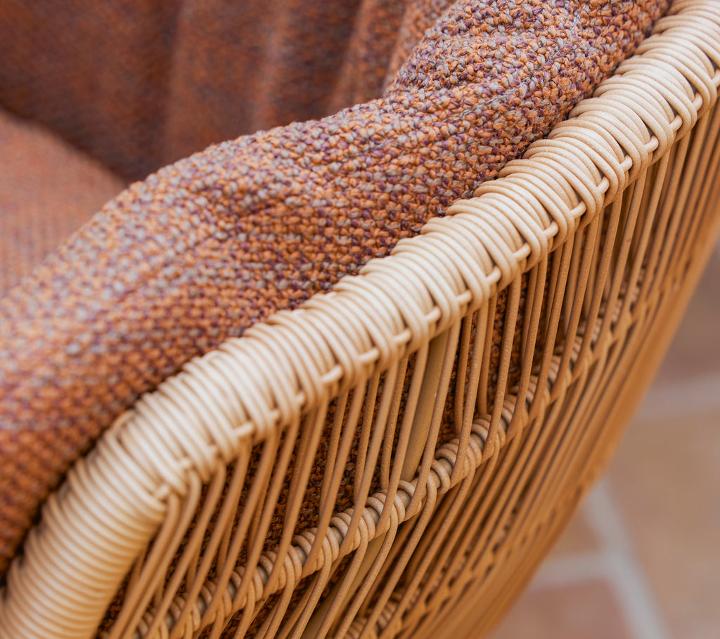 Primer plano de una silla de comedor Stay con un cojín Rise texturizado marrón y un marco de fibra natural trenzada.