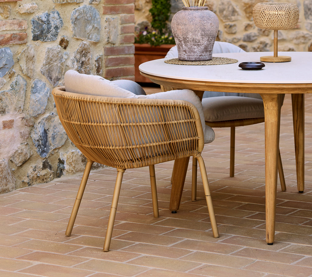 Una silla de comedor Stay con patas de aluminio complementa una elegante mesa de comedor Aspect, rodeada de elementos decorativos.