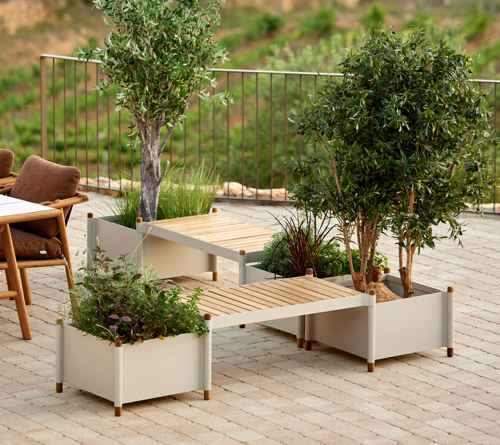 Un banco elegante con dos jardineras, adornado con vegetación, que realza la estética exterior con un toque natural.