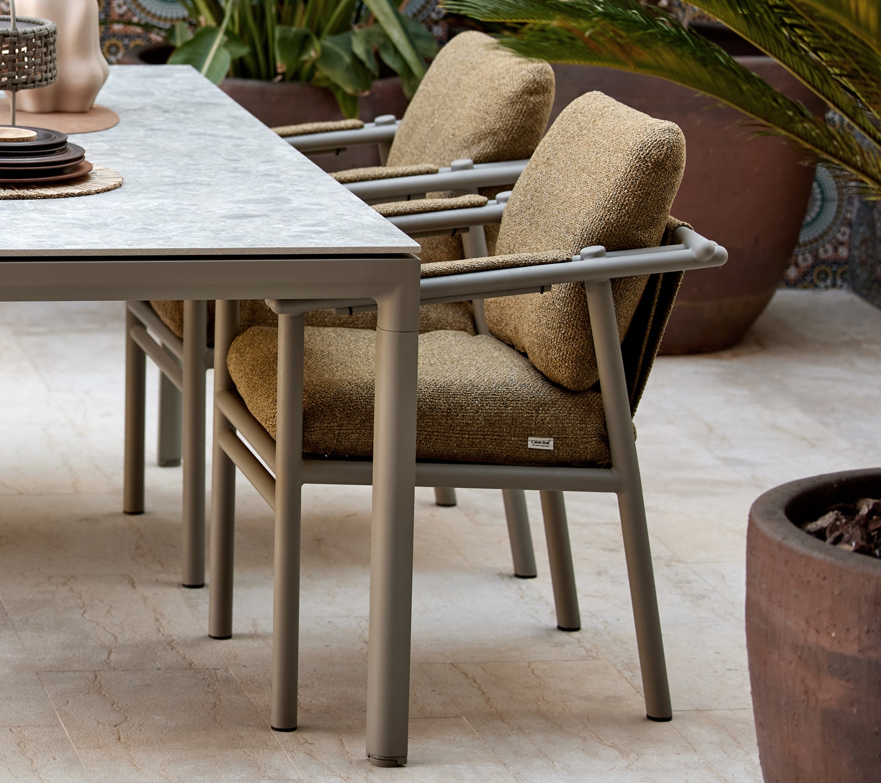 Dos sillas de comedor con cojines suaves, que presentan un diseño moderno con patas robustas, situadas junto a una mesa con elementos decorativos.