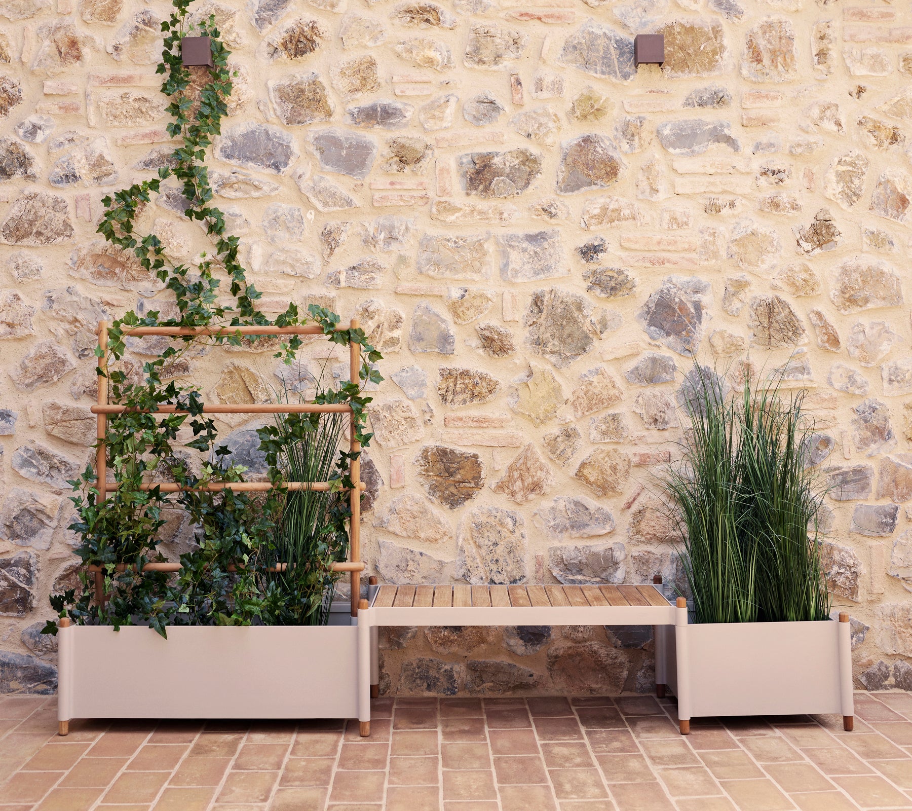Banco de plantas Sticks con vegetación contra una pared de piedra, que presenta un soporte de plantas vertical y dos grandes macetas.