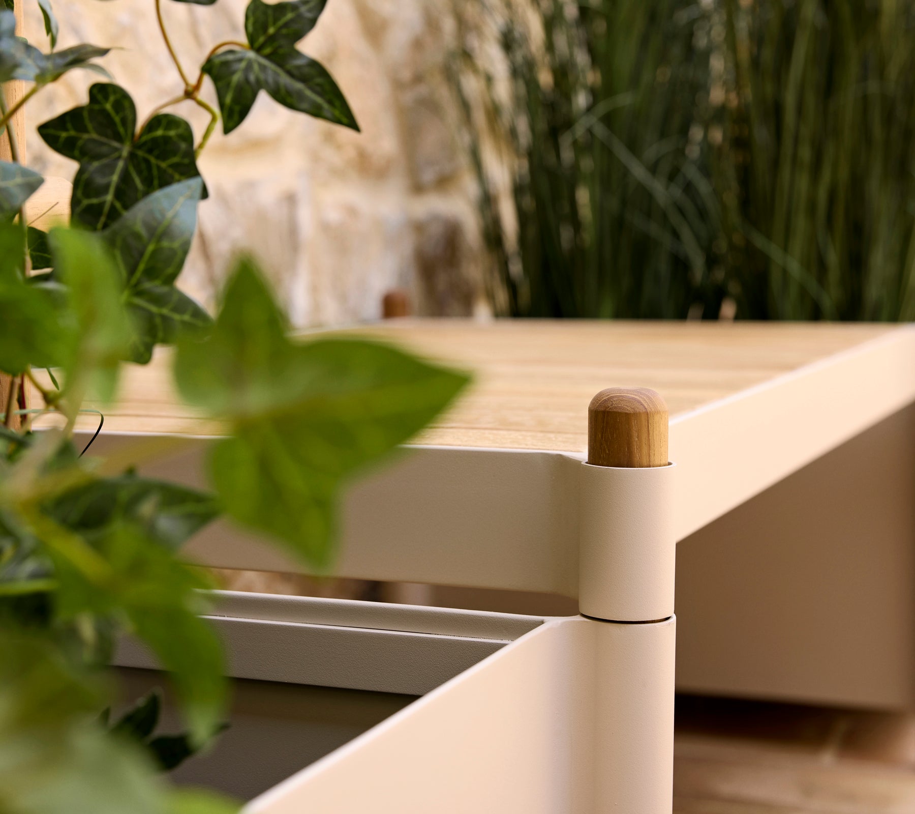 Un banco elegante con una parte superior de madera y bordes suaves, acompañado de vegetación en una maceta, que realza una atmósfera serena.