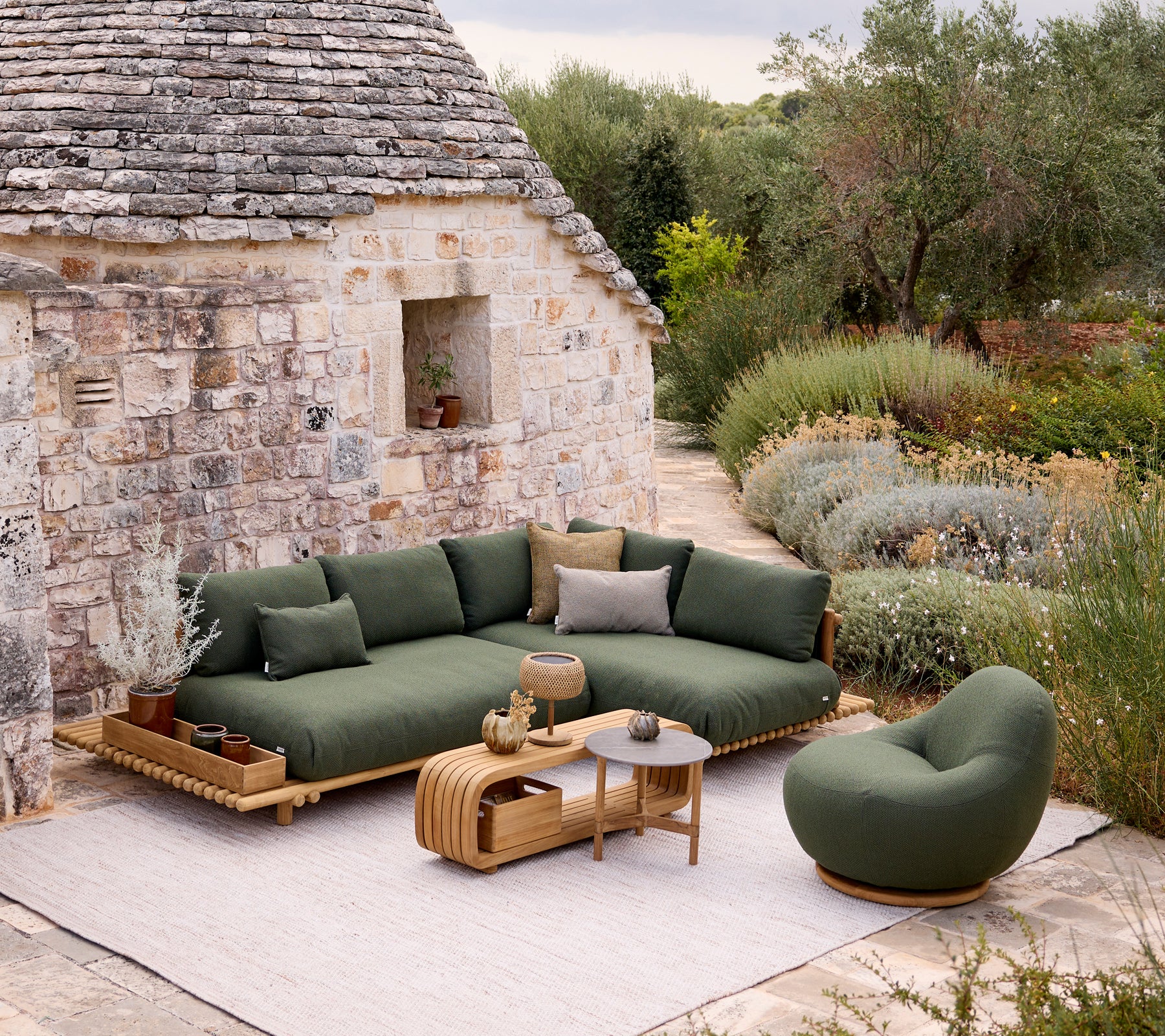 Sofá y silla verdes modernos con una mesa marrón en un entorno de jardín.