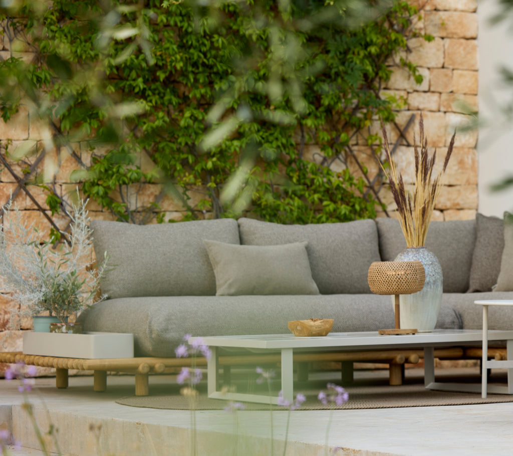 Sofá gris moderno con una mesa de madera en un elegante área de salón al aire libre.
