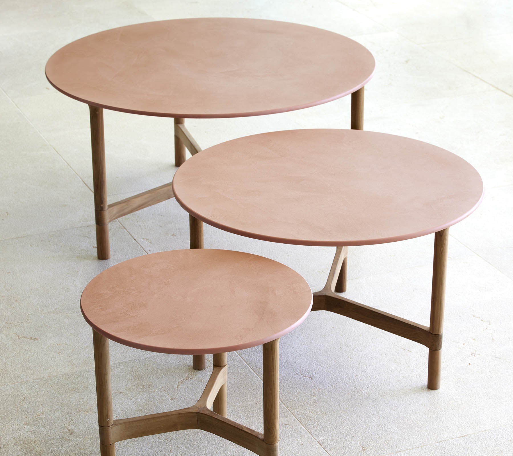 Tres mesas de café circulares de diferentes tamaños, con un diseño minimalista, patas de madera y una superficie suave y elegante.