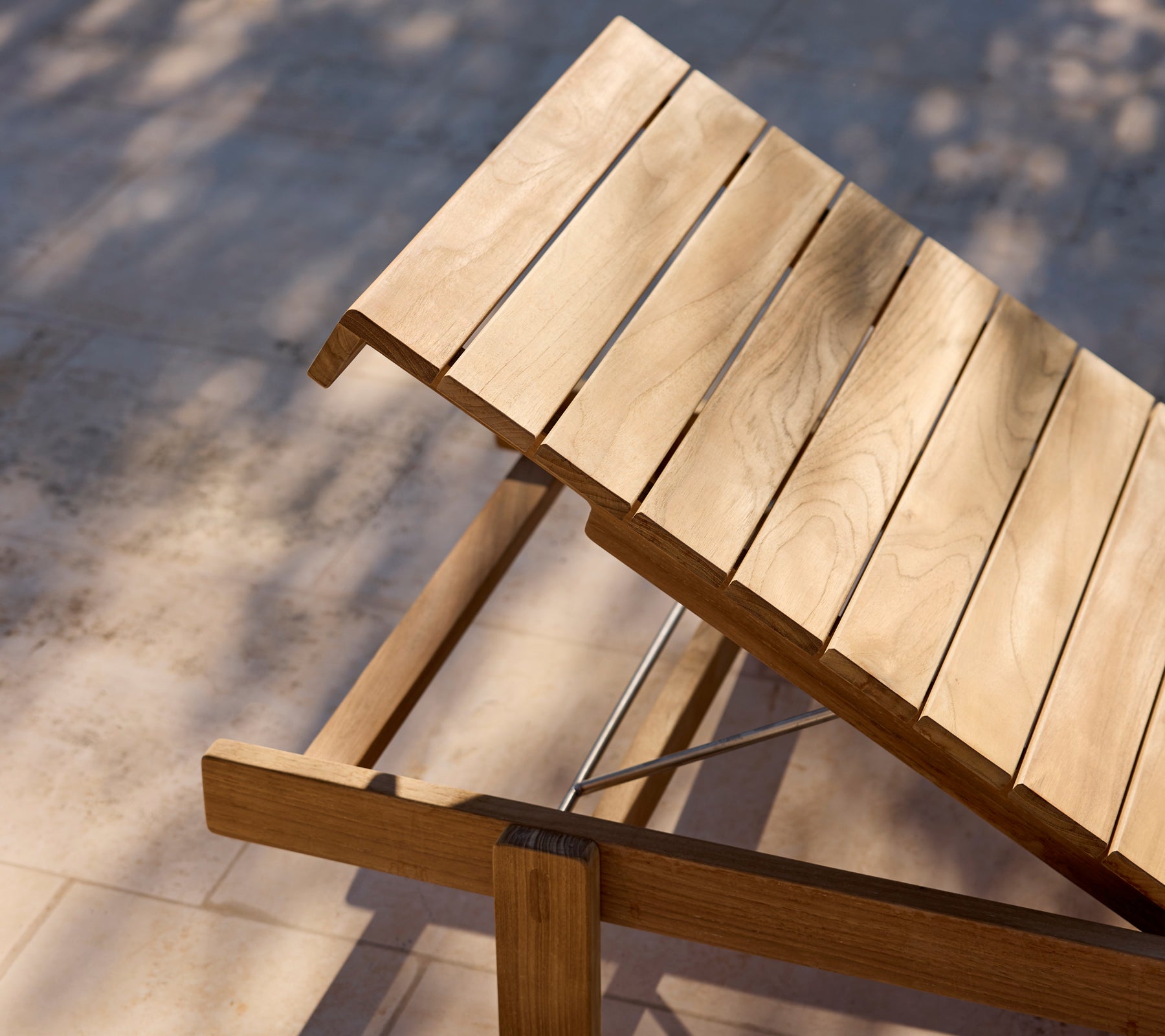 Silla de lounge de madera moderna con respaldo ajustable en un patio soleado.