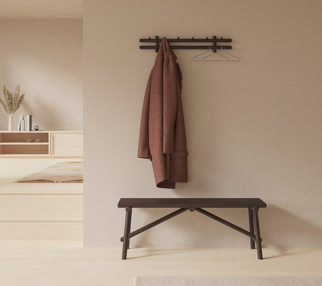 Un entorno minimalistico con un banco de madera y un abrigo colgado en un estante montado en la pared, realzando la simplicidad y la funcionalidad del espacio.