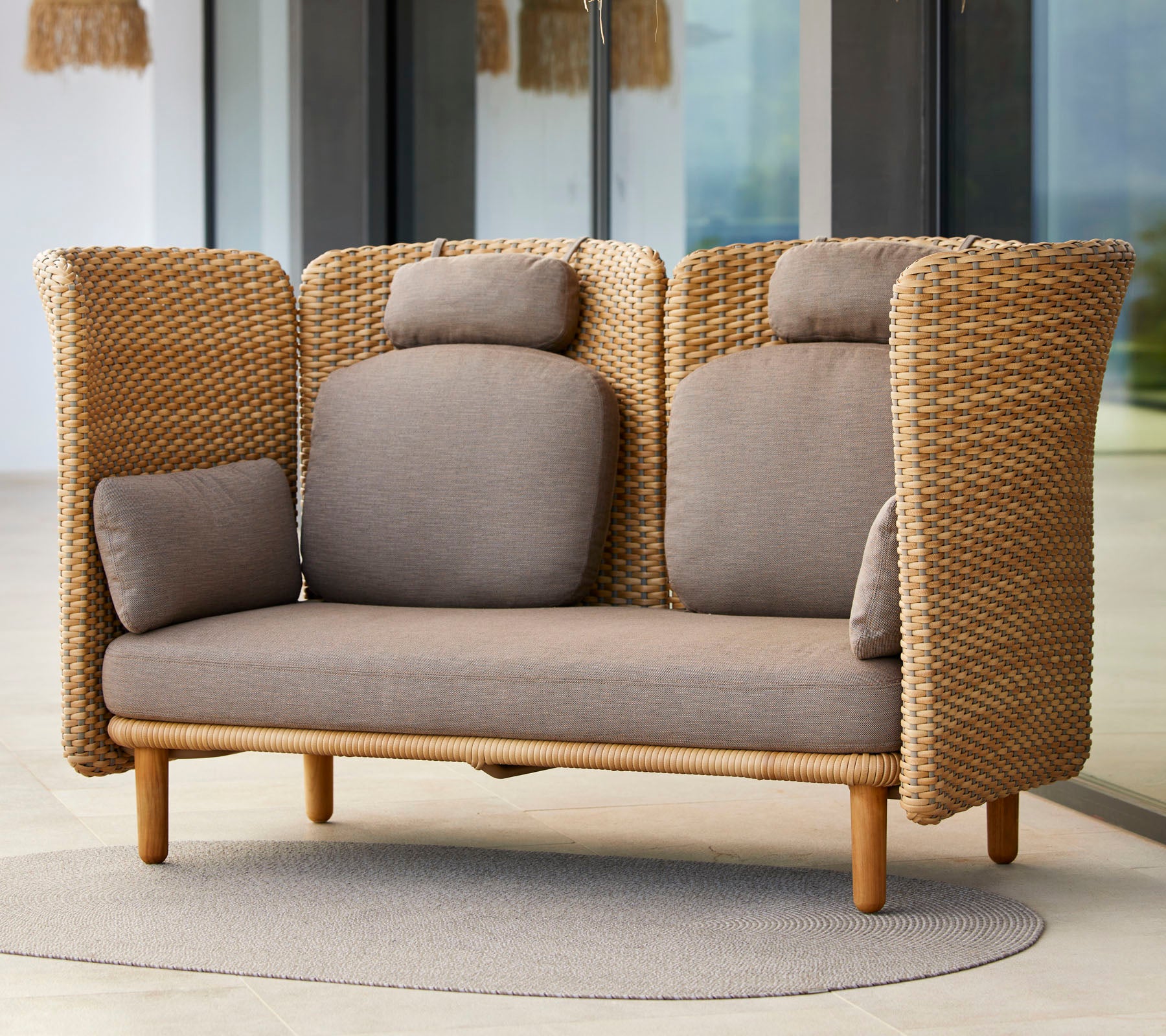 Sofá de dos plazas elegante con textura tejida, que cuenta con cómodos cojines y una base de madera natural, ideal para relajarse.